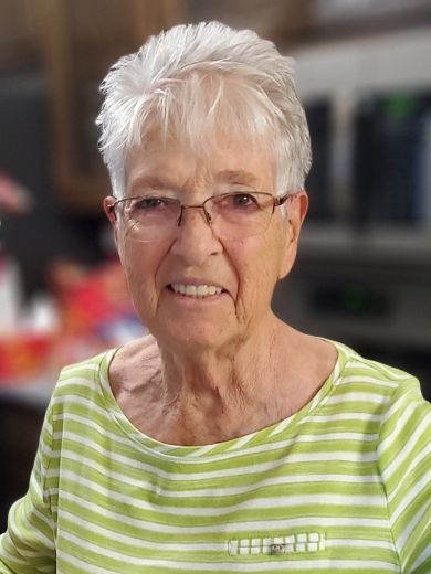 Lois smiles. She wears thinly framed glasses and a striped shirt.