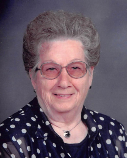 Viola Albers wears a navy, polka-dot blouse in front of a blue backdrop.