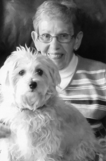 Shirley smiles with her dog on her lap.