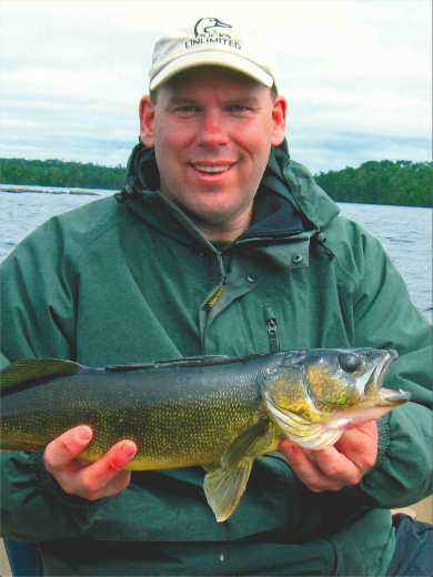 Paul smiles, holding a large fish.